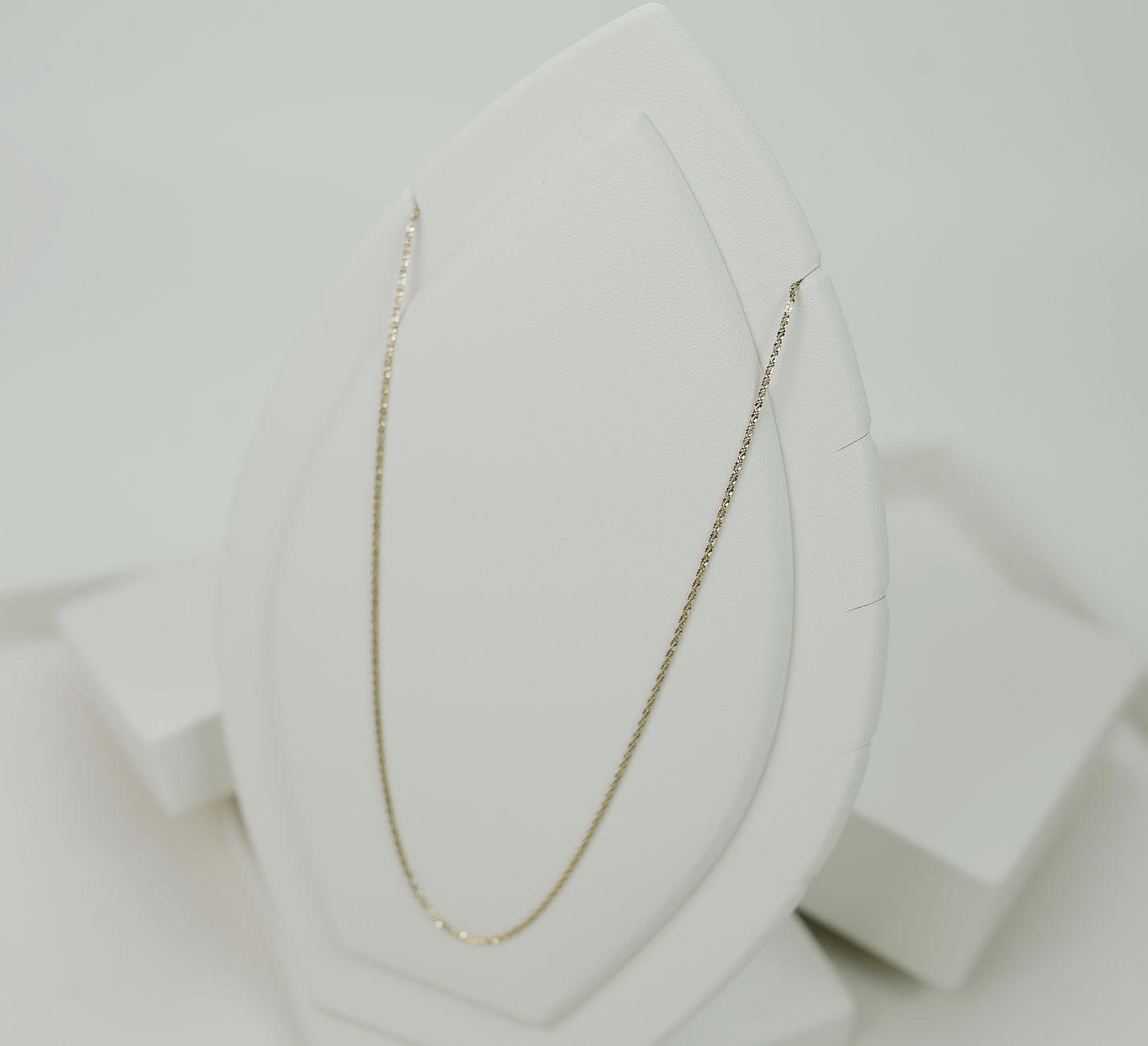 A fine necklace displayed on a white stand